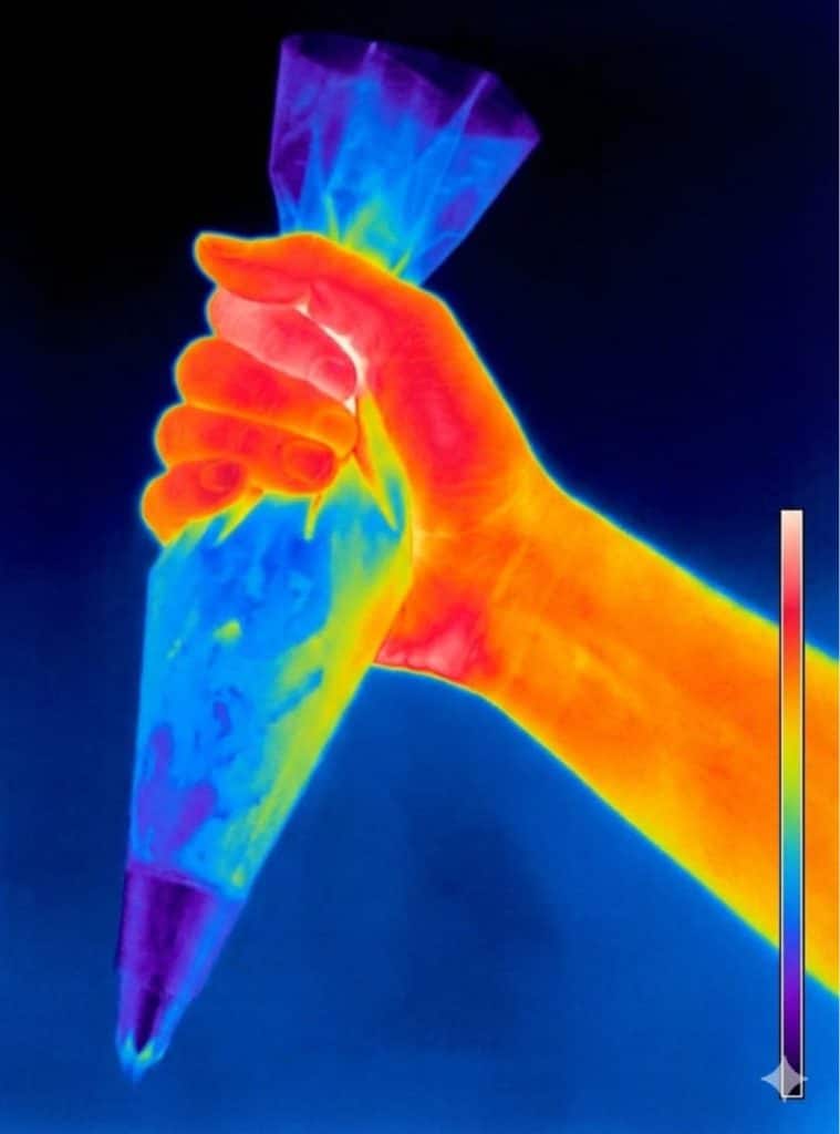 Vue thermique montrant la chaleur de la main qui réchauffe la crème dans la poche à douille.